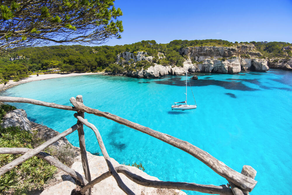 Barca a vela vicino la bella spiaggia di Cala Macarella, isola di Minorca, Spagna.